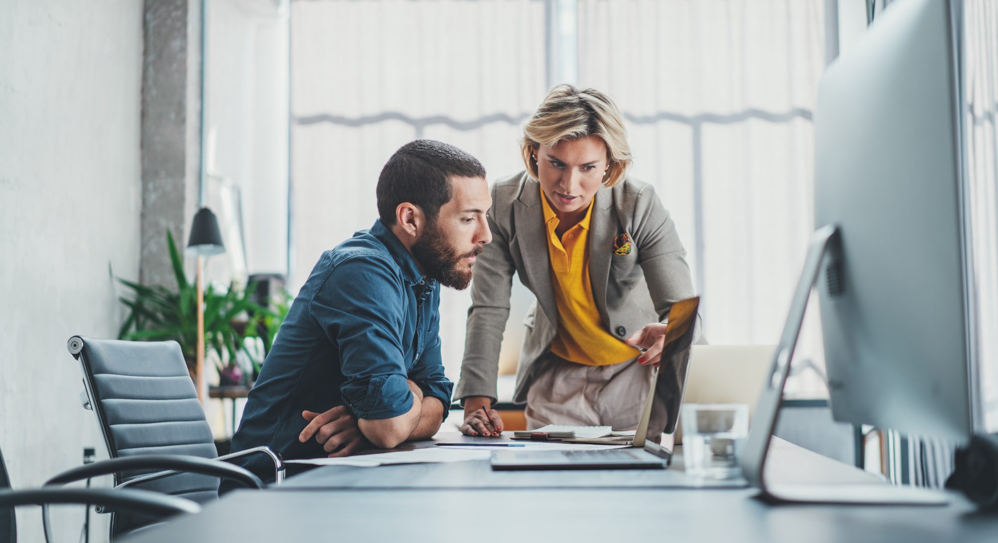 man and woman in the office looking at laptop